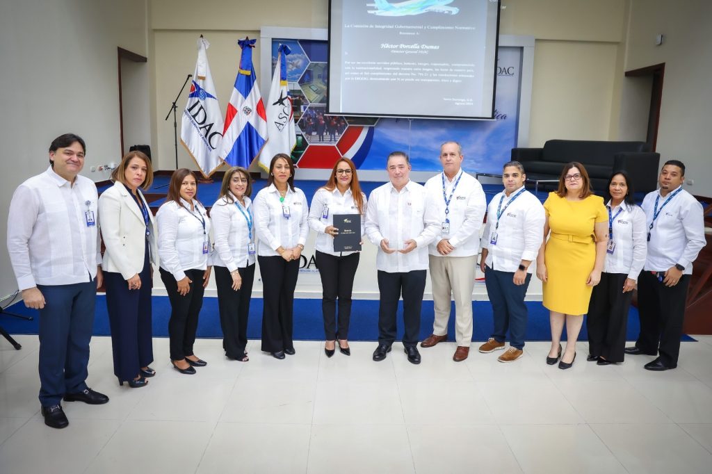 Héctor Porcella, director general del IDAC; recibiendo de parte de Igris Bonnelly, coordinadora general de la Comisión de Integridad Gubernamental el reconocimiento.