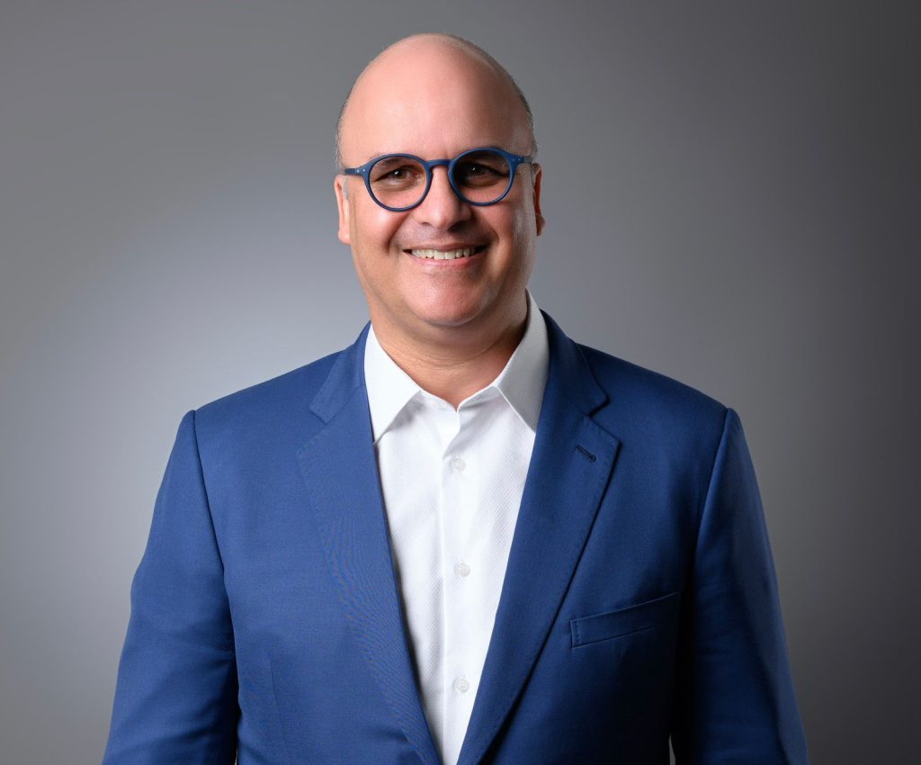 Retrato de Igor David Rodríguez Durán, Director General del Instituto Dominicano de Aviación Civil, sonriendo con un traje azul.