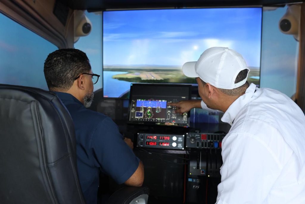 Primeros visitantes al stand del IDAC en la Feria Regional del Libro y la Cultura viviendo la experiencia del Simulador de Vuelo.